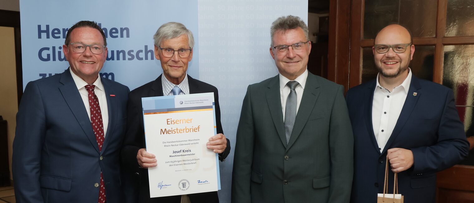 Überreichung der Urkunde zum Meisterjubiläum durch Herrn Klaus Hofmann, der Jubilar hält die Urkunde vor sich.