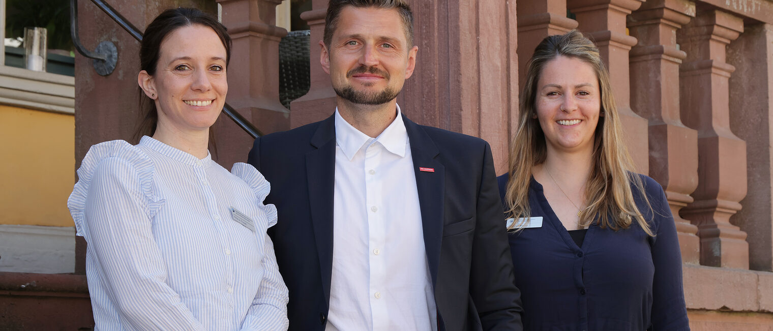 Ein Teil des Meisterprüfungsteams, Melanie Rosvall, Alexander Dirks, Hannah Knoth, stehen vor der Sandsteintreppe des Hotel Prinz Carl.