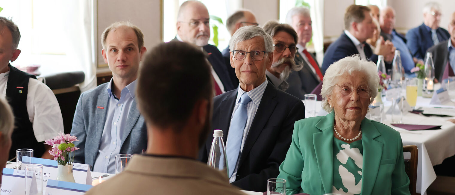 Gäste, Jubilare und Begleitpersonen sitzen am Festlich eingedeckten Tisch.