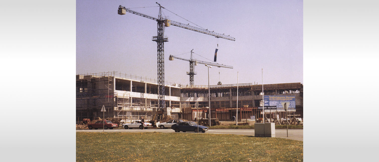 Die Fotografie zeigt den Rohbau der Bildungsakademie und zwei Kräne. 