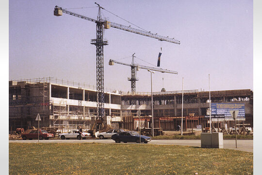 Die Fotografie zeigt den Rohbau der Bildungsakademie und zwei Kräne. 