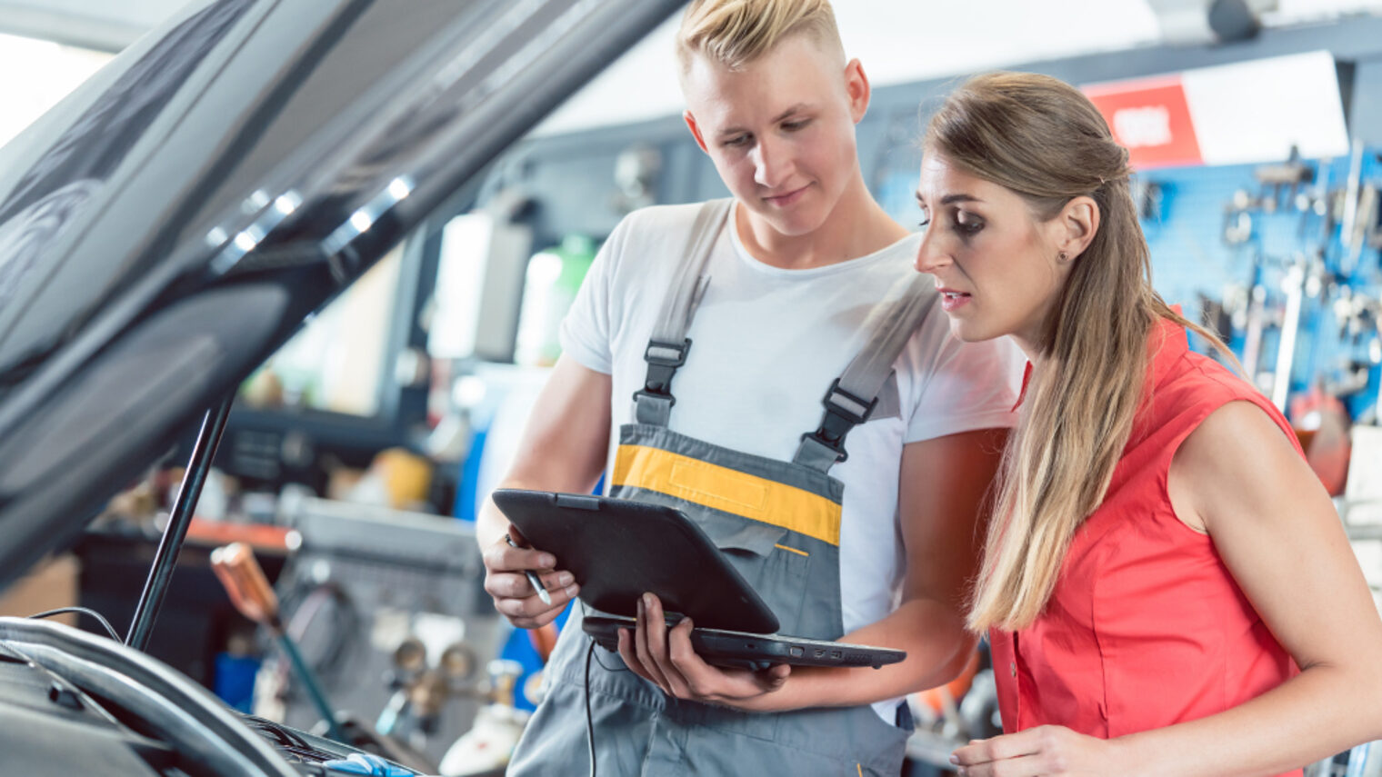 Automechaniker zeigt einer Kundin die Motorfehlercodes.