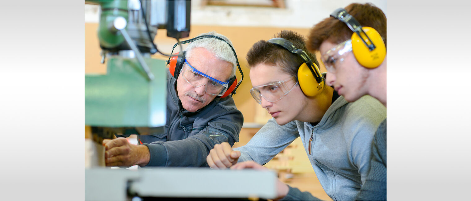 Ausbildung, Lehrling, Berufsorientierung Mann weist Azubis an Maschine ein