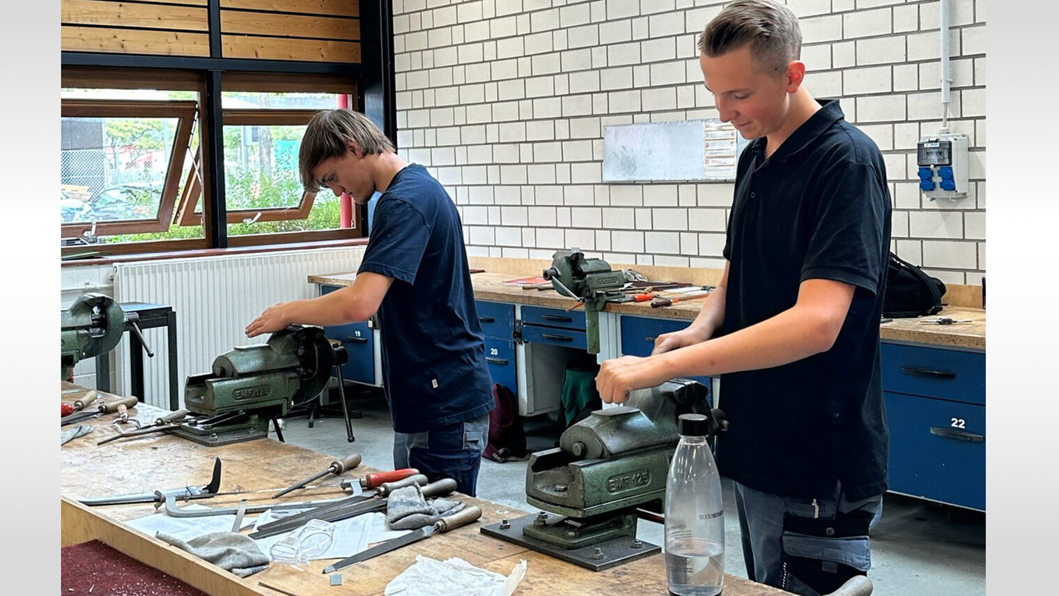 Zwei Jungs stehen vor einem Tisch und arbeiten an einer Maschine. 