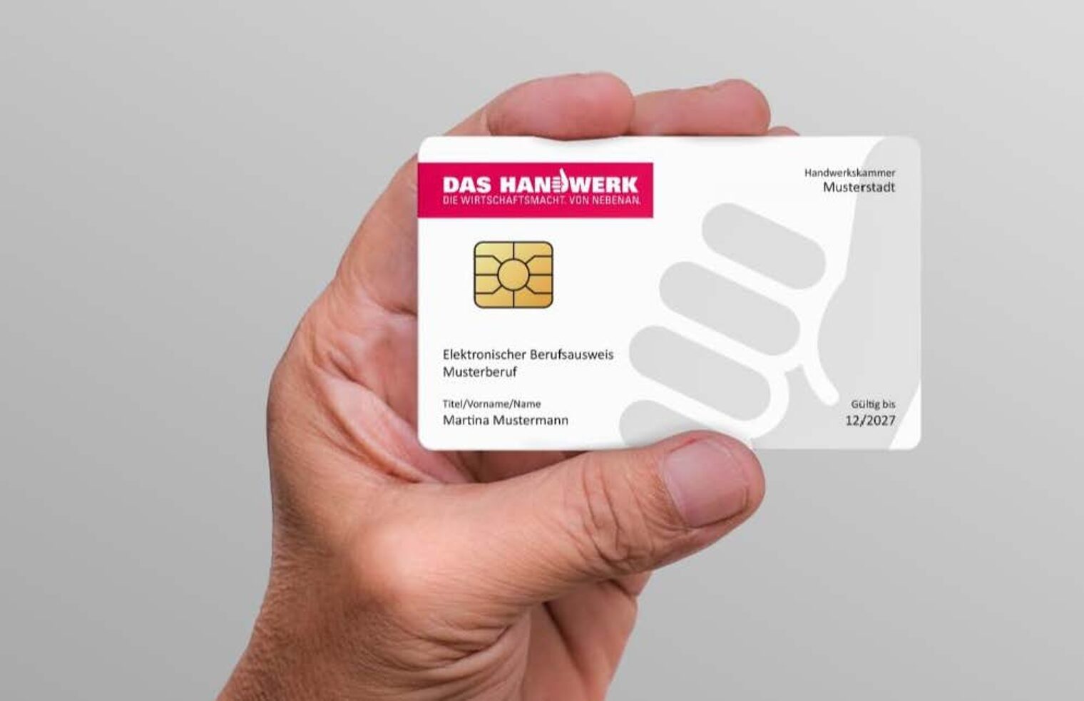 Die Gesundheitskarte wird für Gesundheitshandwerke verpflichtend Hand hält eine Karte mit stilisiertem Daumen in Grau, der Aufschrift "Das Handwerk" auf einem roten Balken, goldenem Emblem und weiteren Schriften