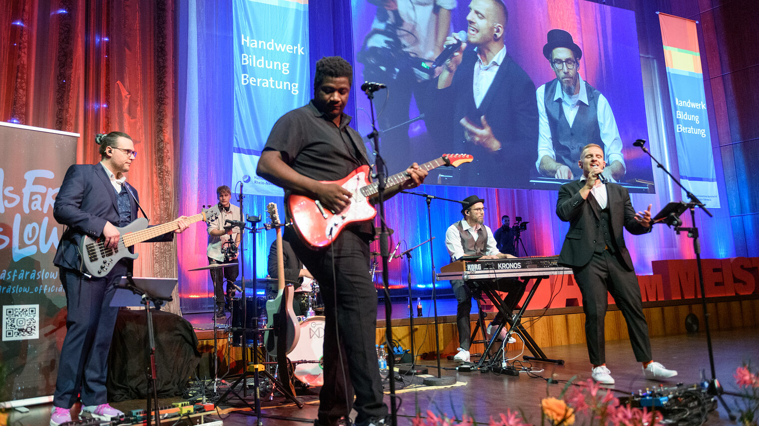 Man sieht 5 Personen die auf der Bühne stehen und Instrumente halten