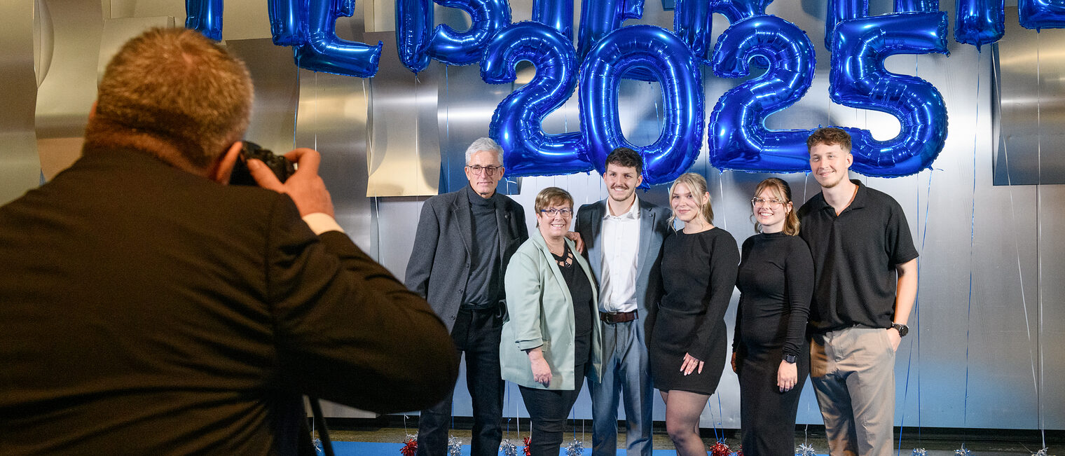Eine Gruppe von Personen steht vor Luftballons und lässt sich fotografieren