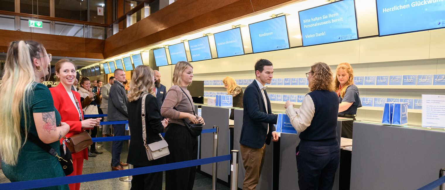 Einige Menschen stehen an um ihren Meisterbrief überreicht zu bekommen