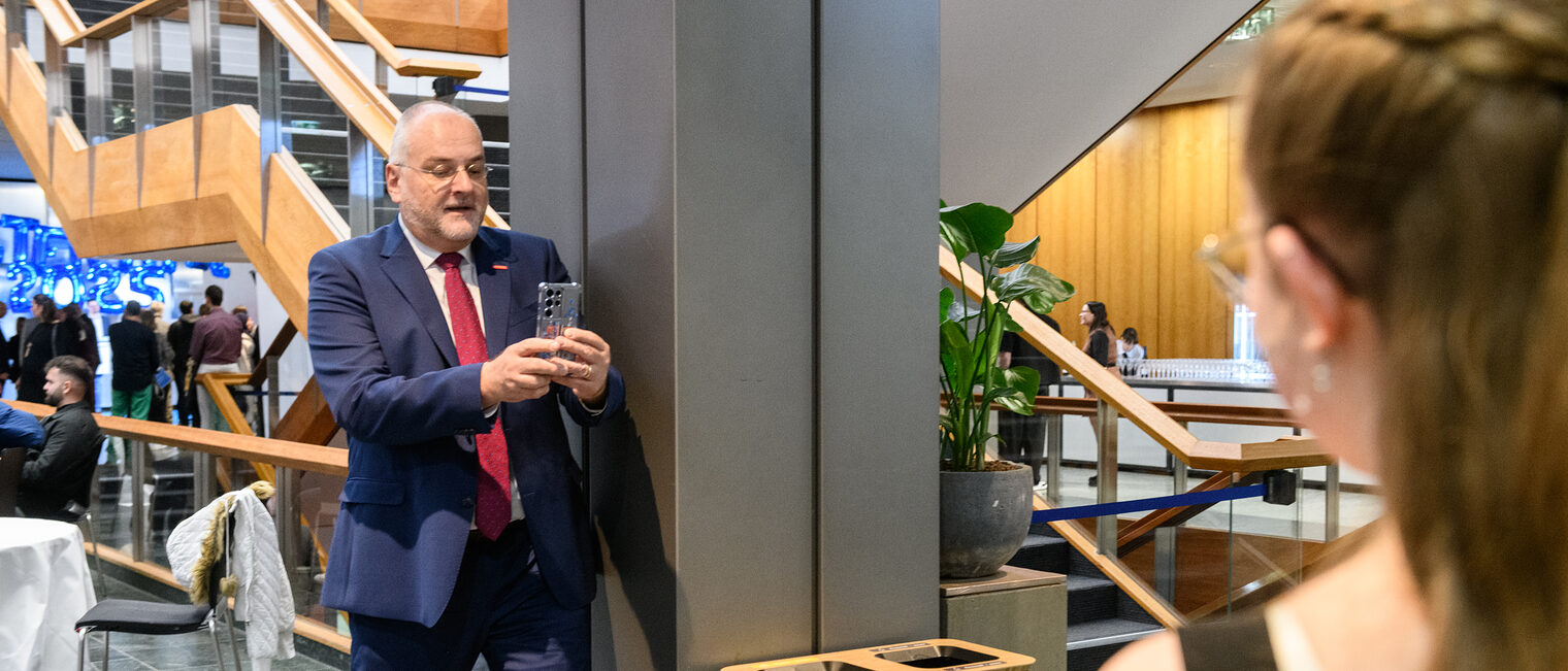 Ein Mann Fotografiert mit einem Handy andere Personen