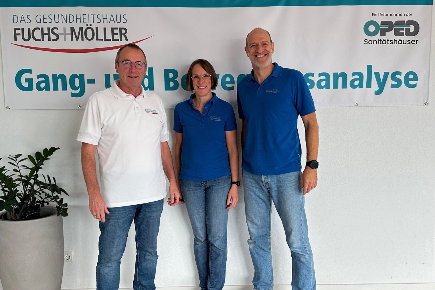 3 Personen stehen vor einem Plakat namens "Fuchs+Möller" und schauen lächelnd in die Kamera.