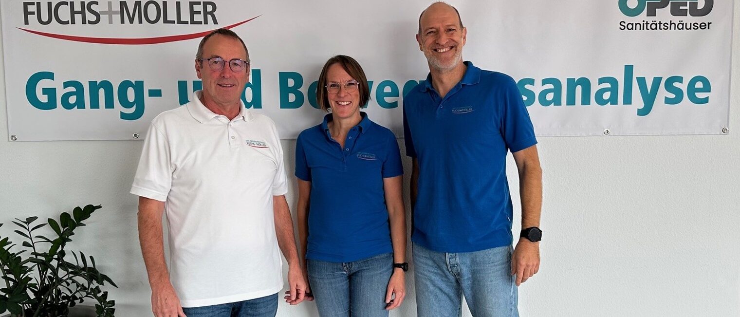 3 Personen stehen vor einem Plakat namens "Fuchs+Möller" und schauen lächelnd in die Kamera.