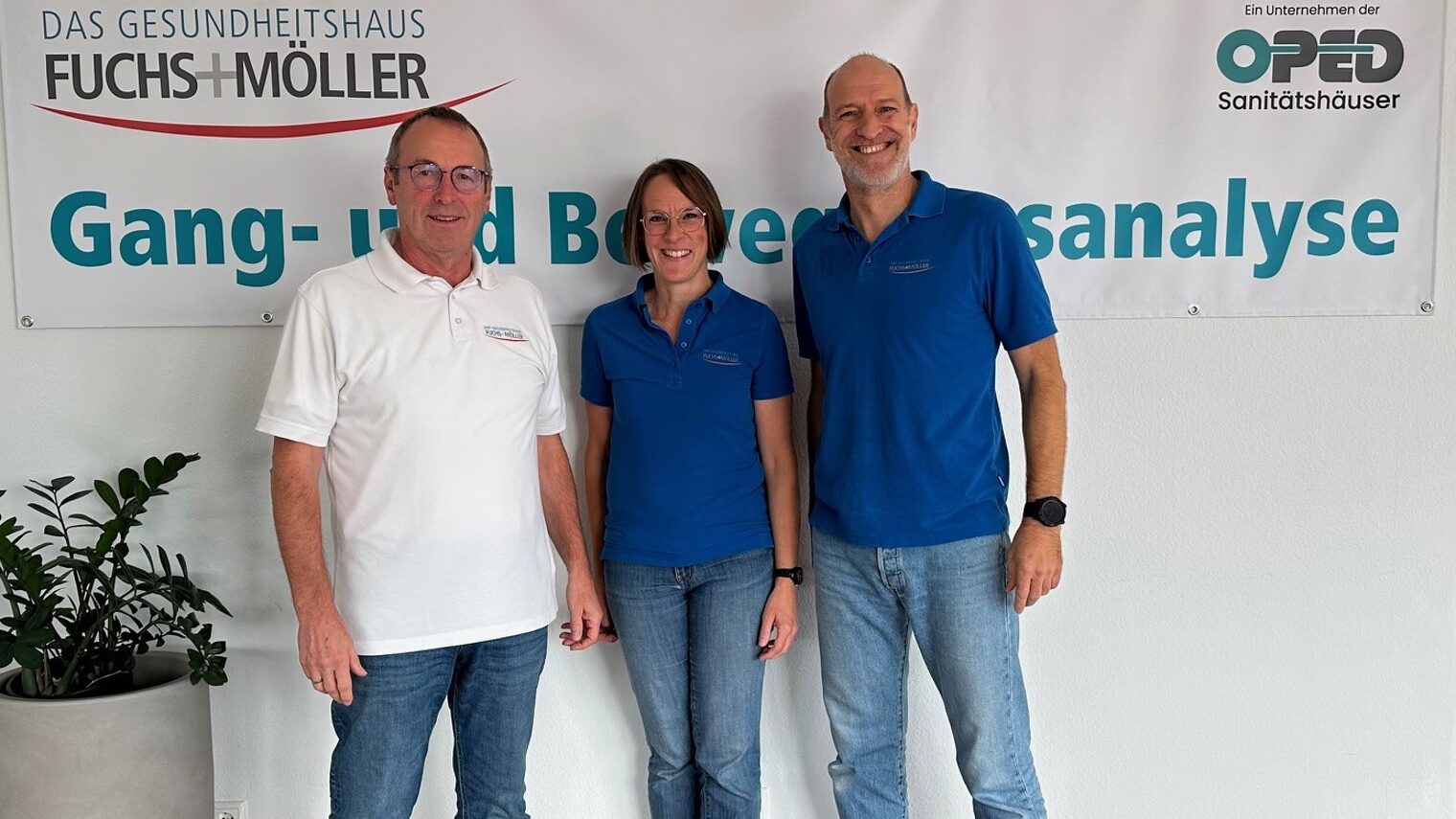 3 Personen stehen vor einem Plakat namens "Fuchs+Möller" und schauen lächelnd in die Kamera.