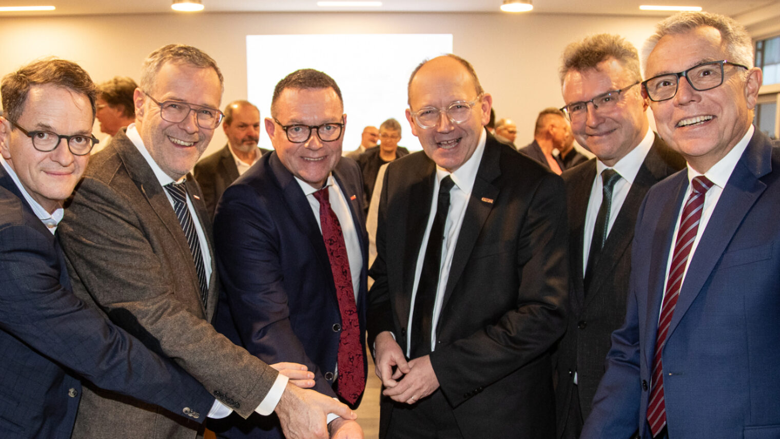 Sechs Männer beim Anschnitt einer Geburtstagstorte