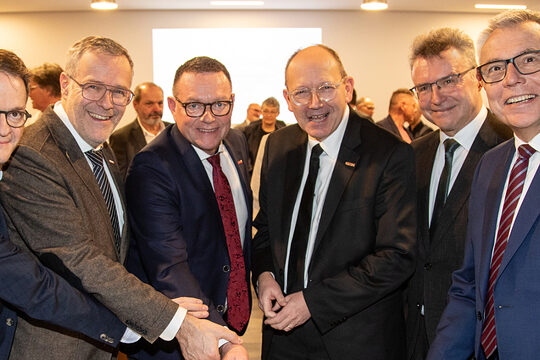 Sechs Männer beim Anschnitt einer Geburtstagstorte