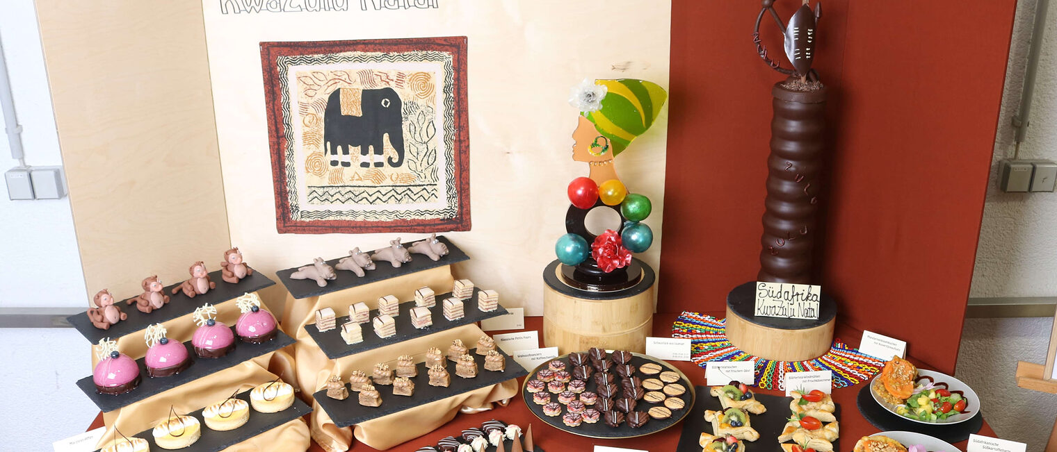 Ein aufgebautes Prüfungsbuffet, ein Tisch mit aufgereihten Törtchen und Kuchen