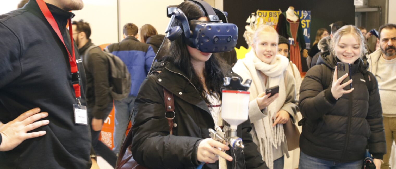 Ein Mädchen auf einer Veranstaltung für Berufe probiert virtuelles Lackieren aus.