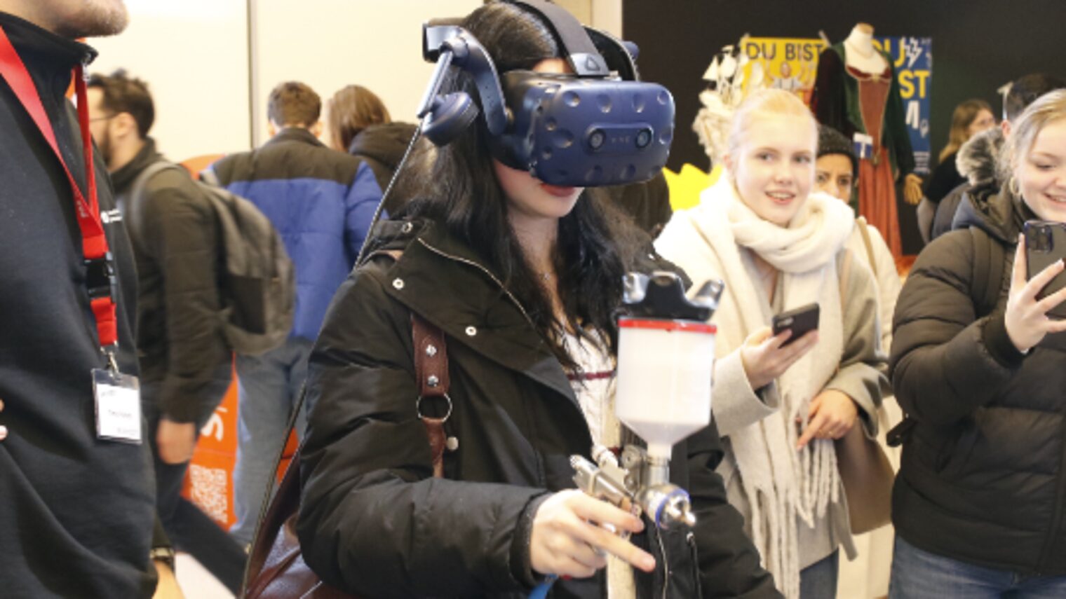 Ein Mädchen auf einer Veranstaltung für Berufe probiert virtuelles Lackieren aus.