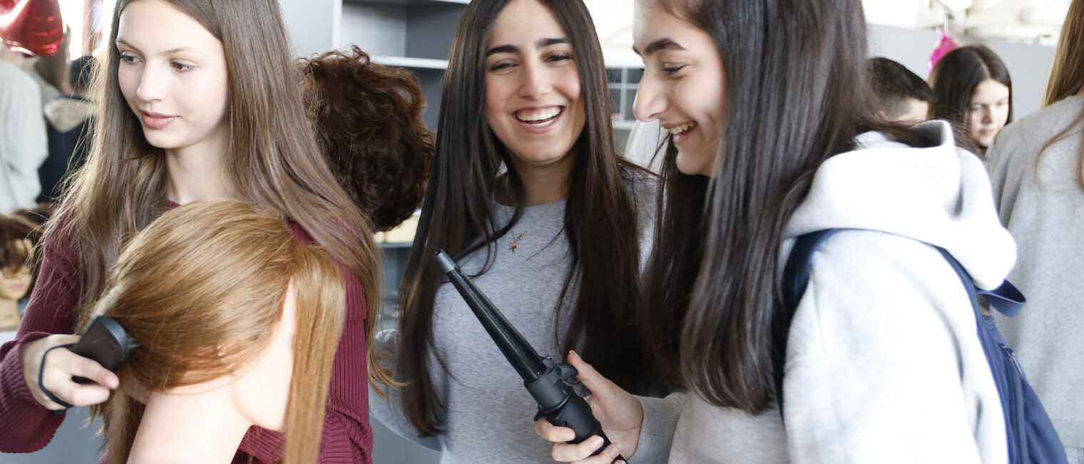 Drei junge Mädchen beim frisieren eines Übungskopfes