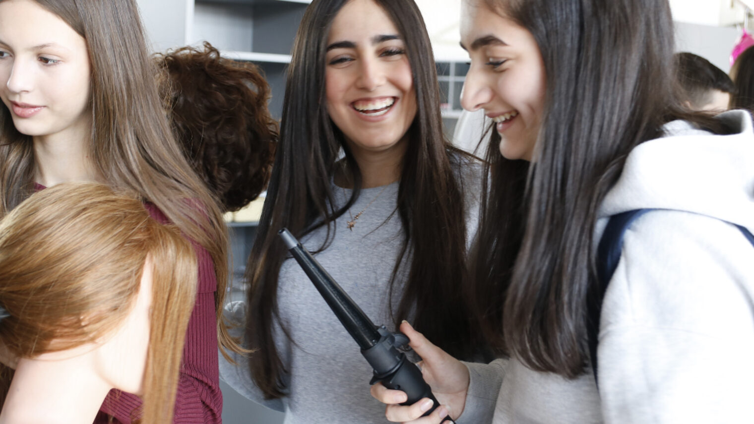 Drei junge Mädchen beim frisieren eines Übungskopfes
