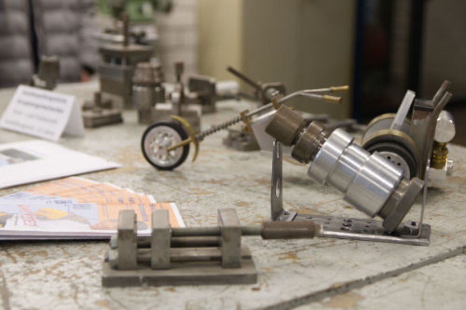 Detailaufnahme von handgefertigten Metallmodellen, darunter ein Fahrzeug, auf einem Werkstatttisch