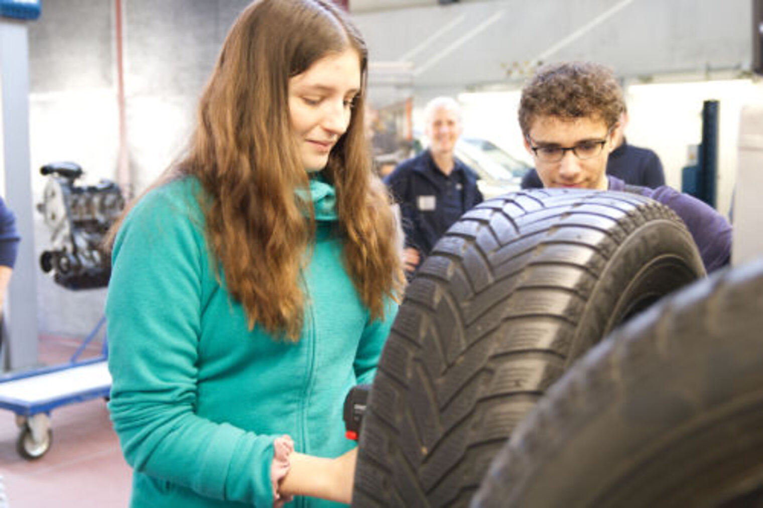 Maedchen die Radmuttern eines Autoreifens in einer KFZ-Werkstatt