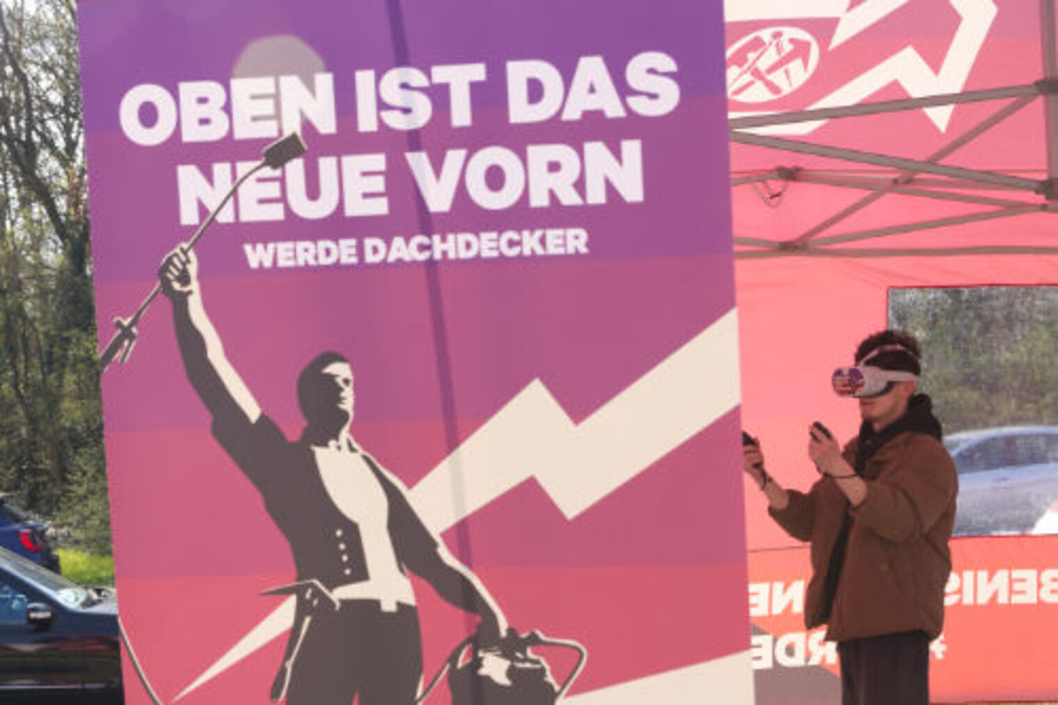 Maedchen mit VR-Brille vor Werbeplakat "Oben ist das neue Vorn - Werde Dachdecker"