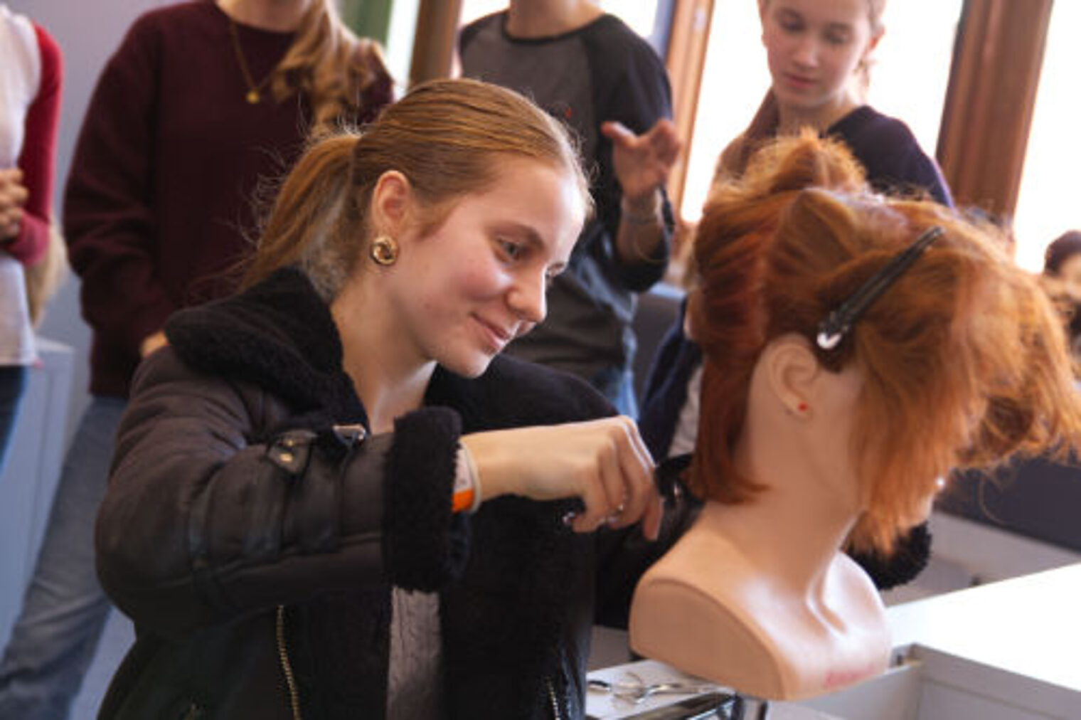 Maedchen uebt das Frisieren an einem Uebungskopf beim Friseur-Stand auf der Berufsmesse