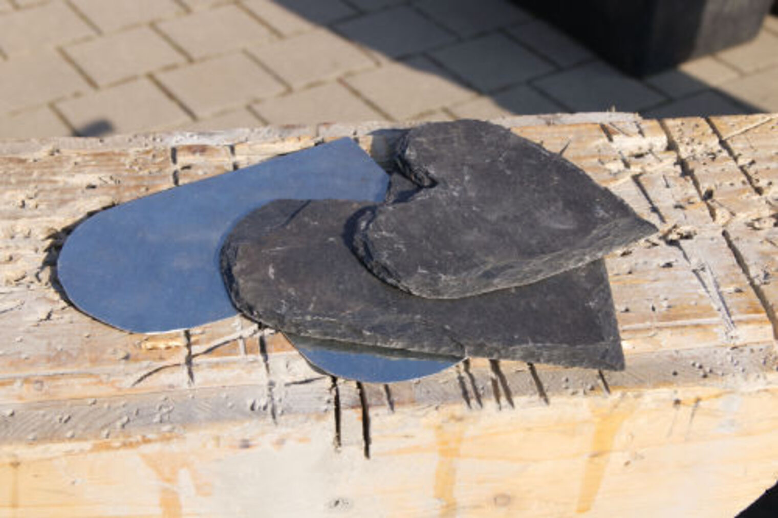 Schieferplatten in verschiedenen Formen auf einem Holzbrett - Dachdeckermaterial zum Anfassen