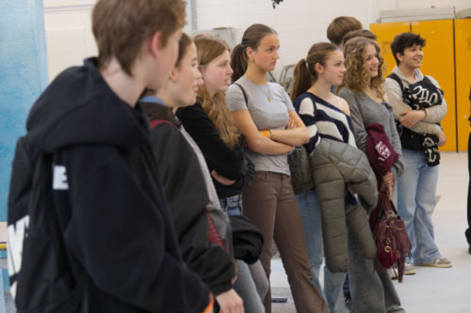 Gruppe Jugendlicher steht in einer Reihe und beobachtet eine Vorfuehrung beim Maler-Stand