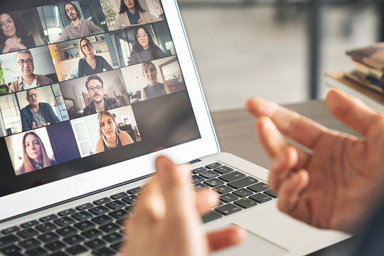 Ein Laptop auf einem Tisch mit einer Videokonferenz und einen Referenten davor.