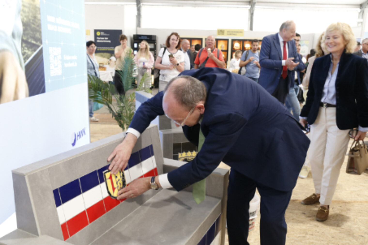 Oberbürgermeister Christian Specht legt bei der Eroeffnung eine Fliese mit Mannheimer Wappen an die geflieste Sitzbank am HWK-Stand auf dem Maimarkt Mannheim