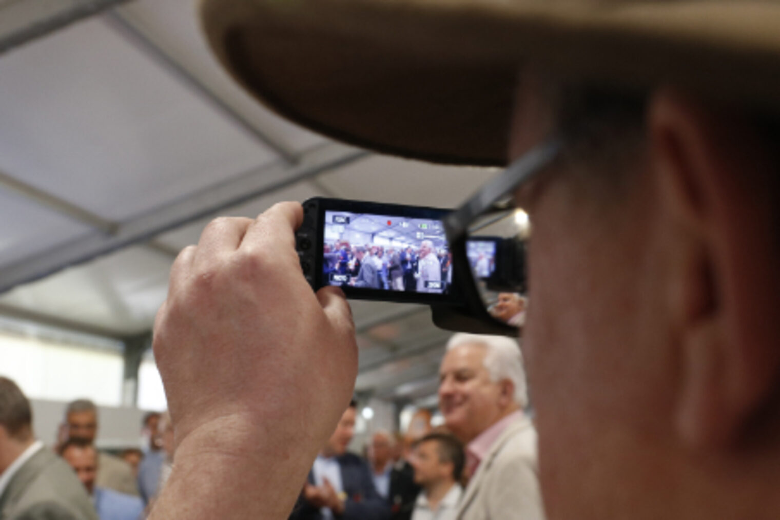 Besucher fotografiert mit seinem Smartphone eine Gruppe bei einer Veranstaltung auf dem Maimarkt Mannheim