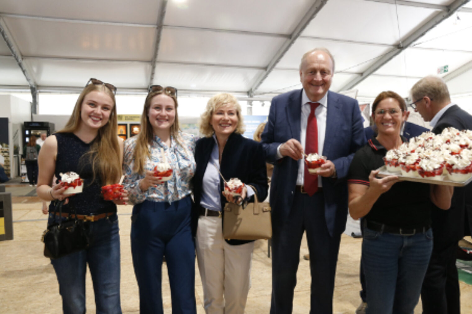 Gruppe von fuenf Personen posiert laechelnd mit Maimarktbecher in der Hand in der Handwerkshalle auf dem Maimarkt Mannheim
