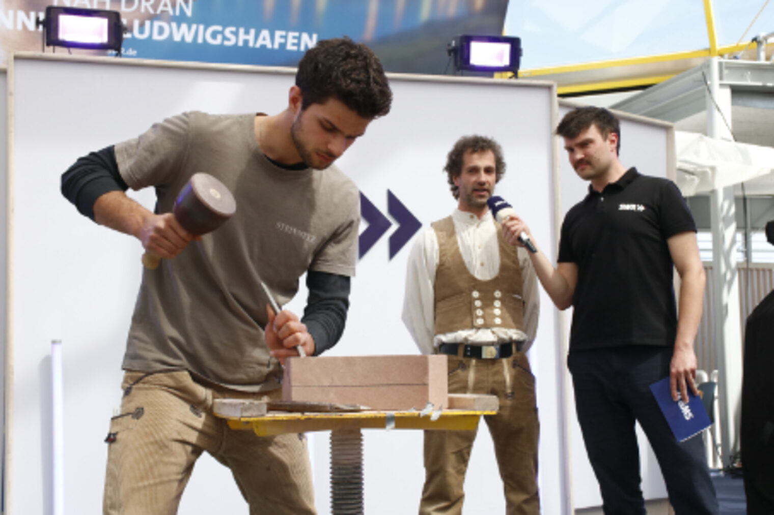 Steinmetz-Azubi bearbeitet live vor Publikum einen Stein auf der SWR-Buehne auf dem Maimarkt Mannheim