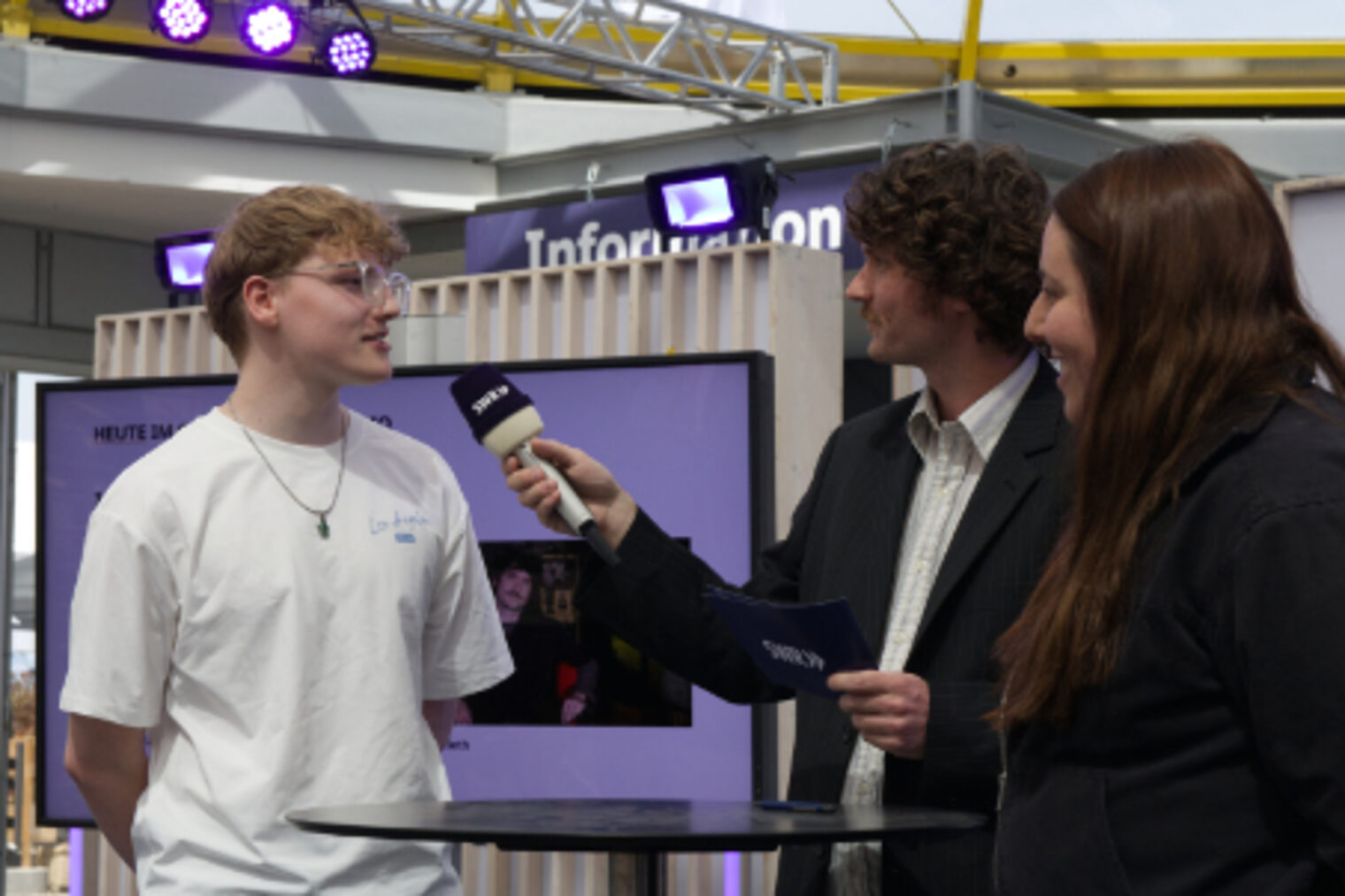SWR-Moderatorin interviewen einen jungen Mann im SWR-Gläsernen-Studio auf dem Maimarkt Mannheim