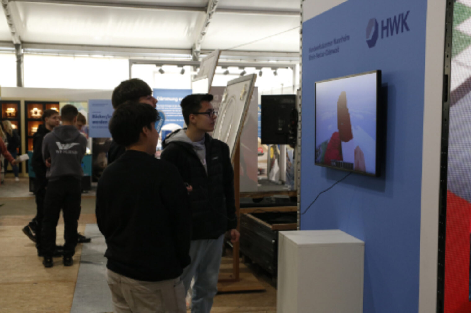 Zwei Jugendliche schauen auf einen Bildschirm am Minecraft-Turm am HWK-Stand auf dem Maimarkt Mannheim