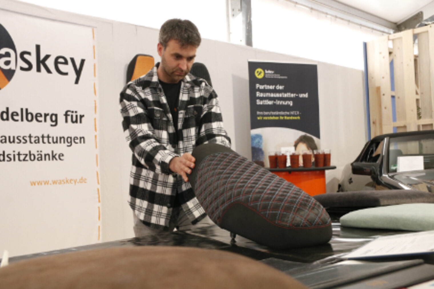 Sattler bearbeitet einen gepolsterten Fahrzeugsitz am Stand der Sattler-Innung auf dem Maimarkt Mannheim