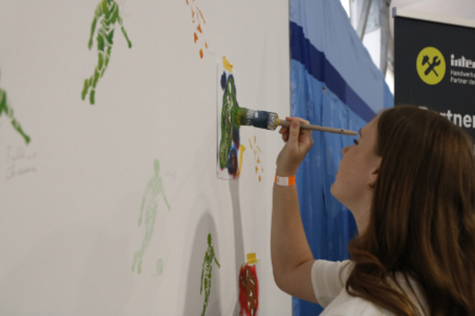 Junges Maedchen tupft mit einem Pinsel ein Bild an eine grosse Wand am Handwerk-Stand auf dem Maimarkt Mannheim