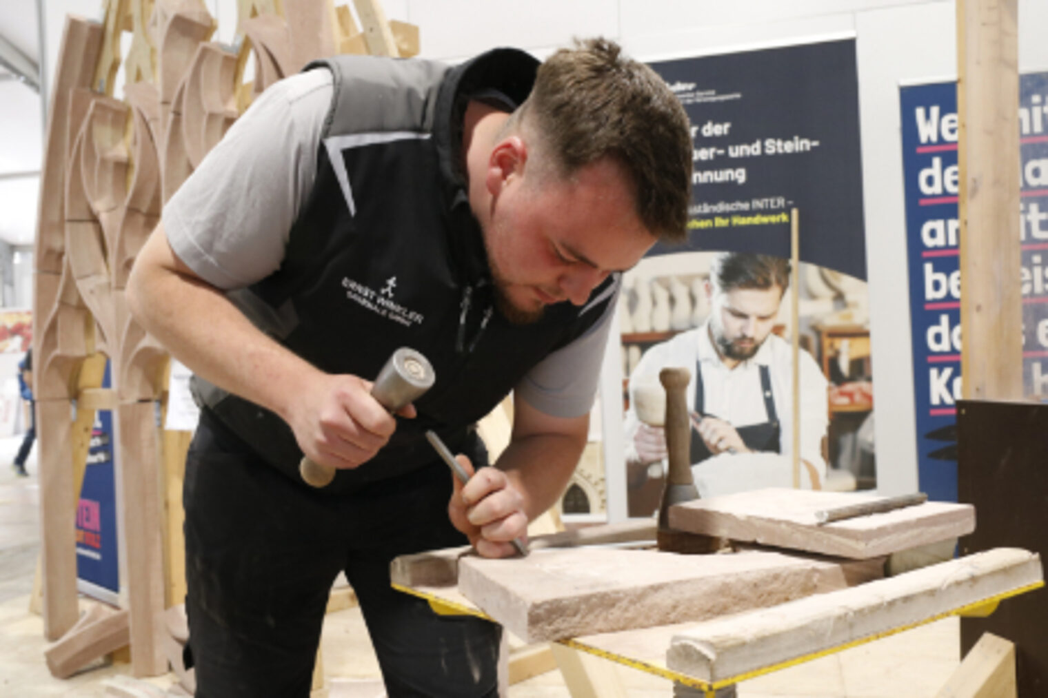 Steinmetz-Handwerker arbeitet konzentriert mit Hammer und Meissel an einem Sandsteinwerkstueck auf dem Maimarkt Mannheim