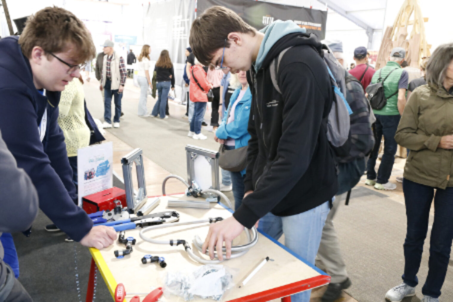 Zwei Jugendliche probieren Sanitaer-Installationsmaterial an einem Messestand auf dem Maimarkt Mannheim aus