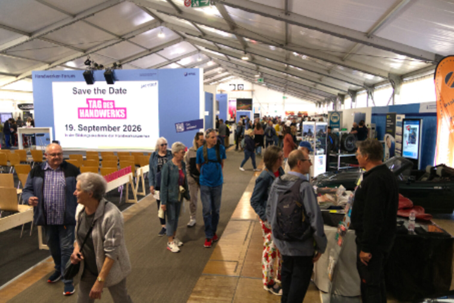 Belebter Messegang in der Handwerkshalle mit Hinweis auf den Tag des Handwerks am 19. September 2026 auf dem Maimarkt Mannheim