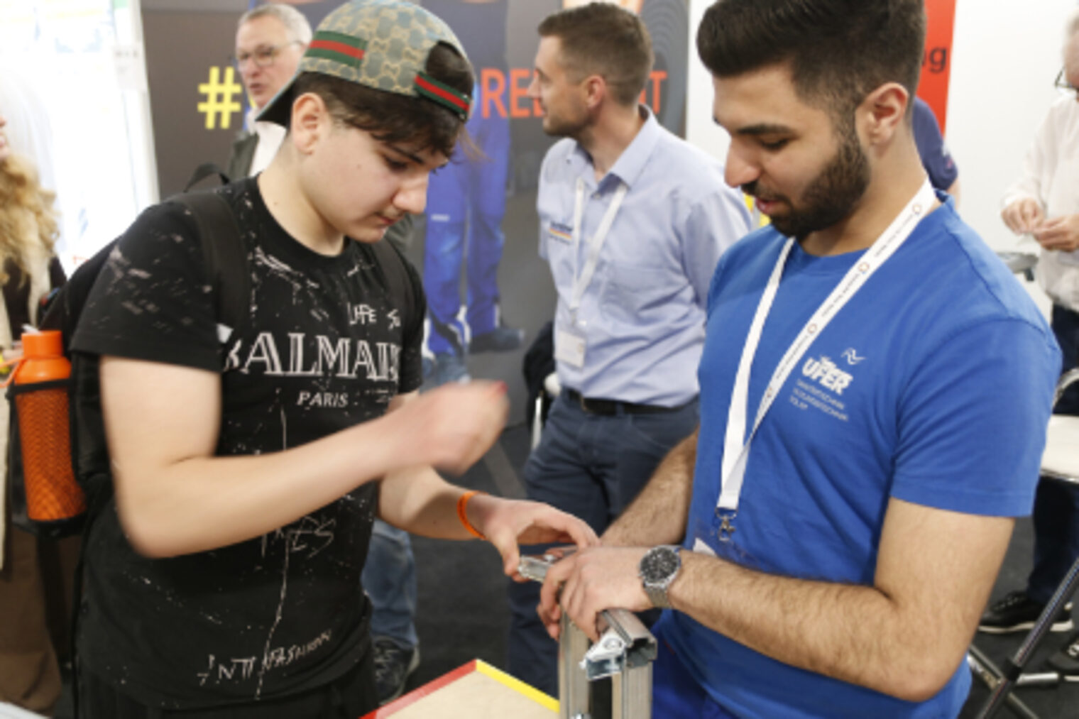 Ausbilder erklaert einem Jugendlichen ein handwerkliches Werkzeug am SHK-Messestand auf dem Maimarkt Mannheim