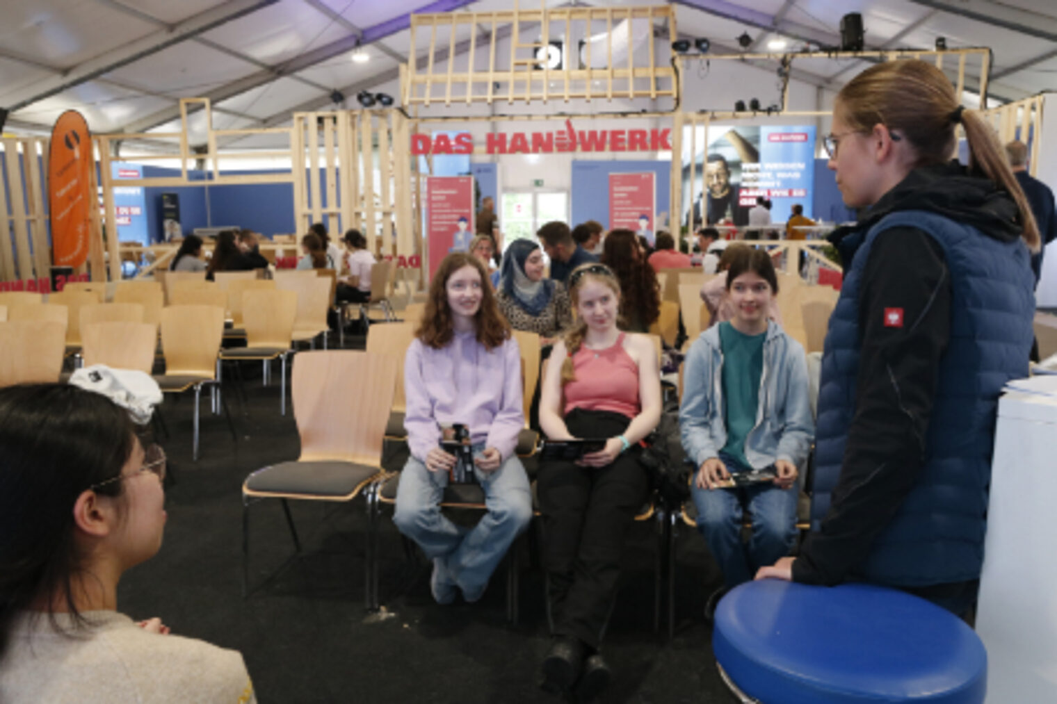 Schuelerinnen sitzen auf Stuehlen im Handwerker-Forum bei der Berufsorientierung auf dem Maimarkt Mannheim
