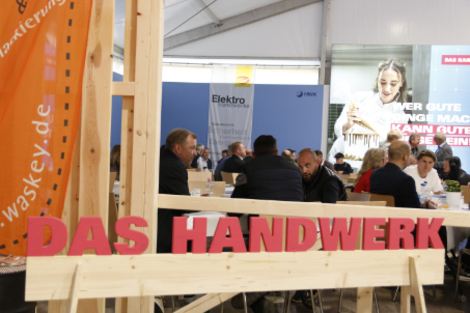 Besucher sitzen an Tischen im belebten Handwerker-Garten auf dem Maimarkt Mannheim