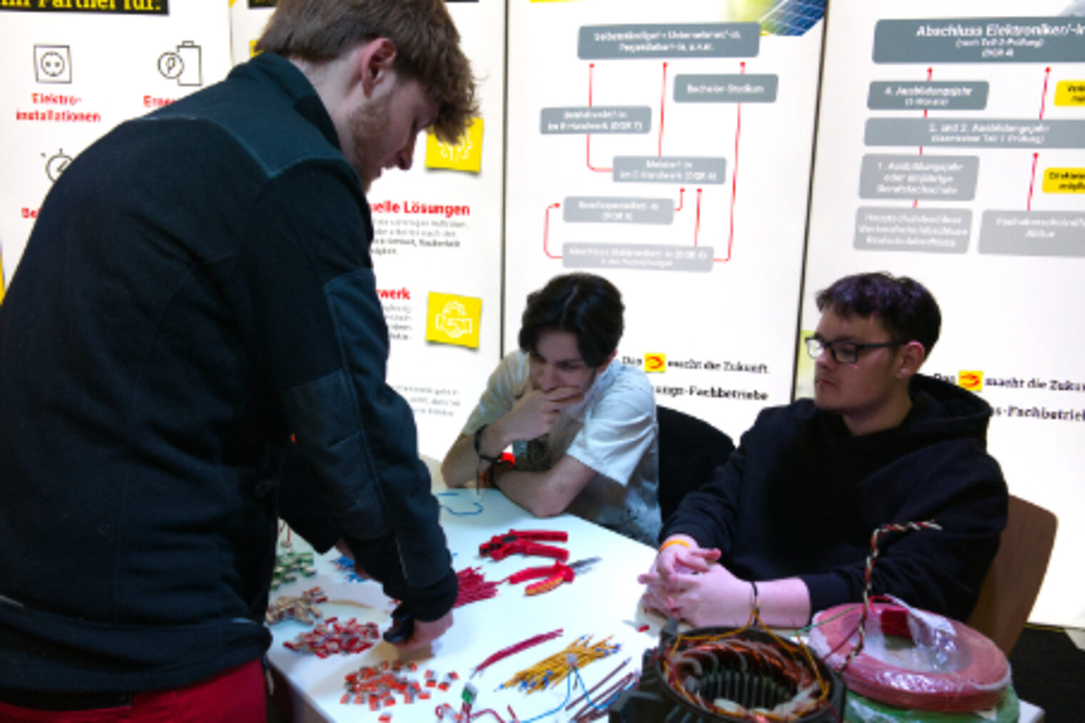 Jugendliche basteln unter Anleitung an Elektrobauteilen und Kabeln am Ausbildungsstand auf dem Maimarkt Mannheim