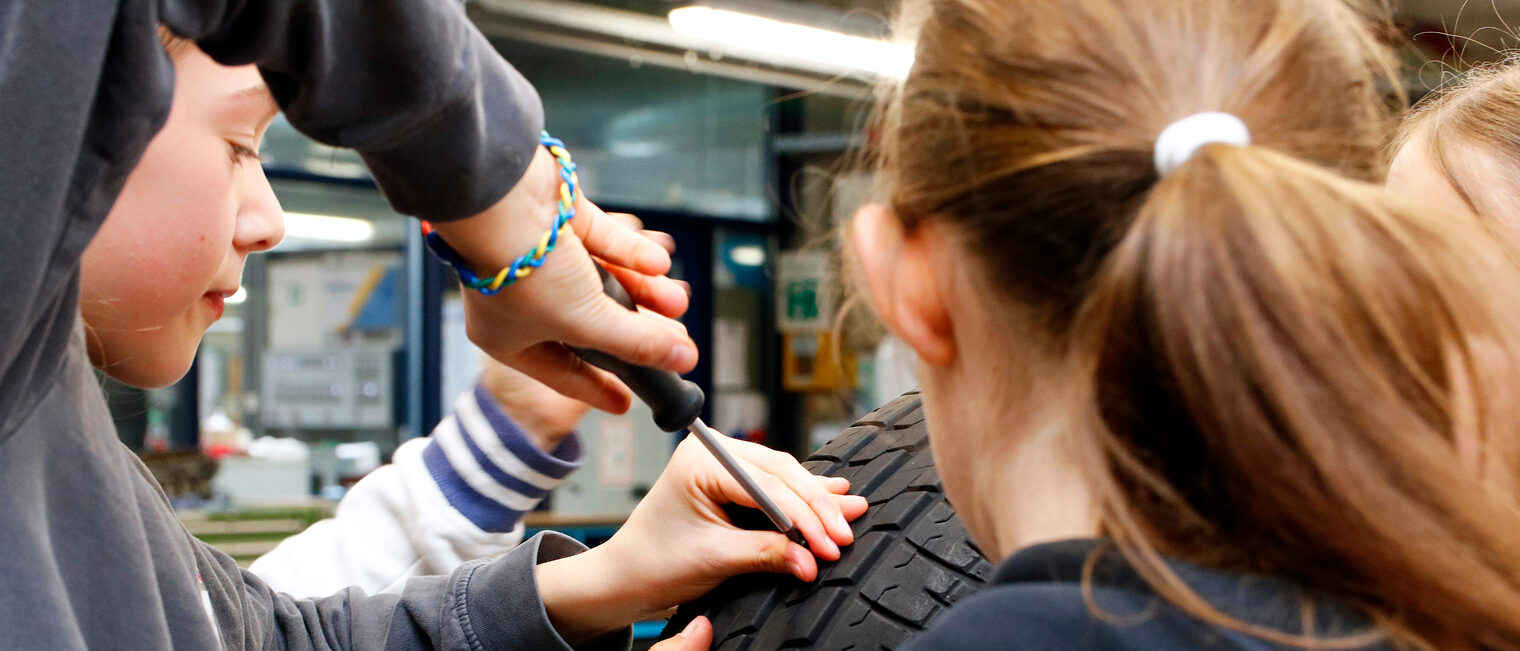 Zu sehen sind Mädchen beim Girls’Day in der Bildungsakademie der Handwerkskammer, an einem Reifen arbeiten.
