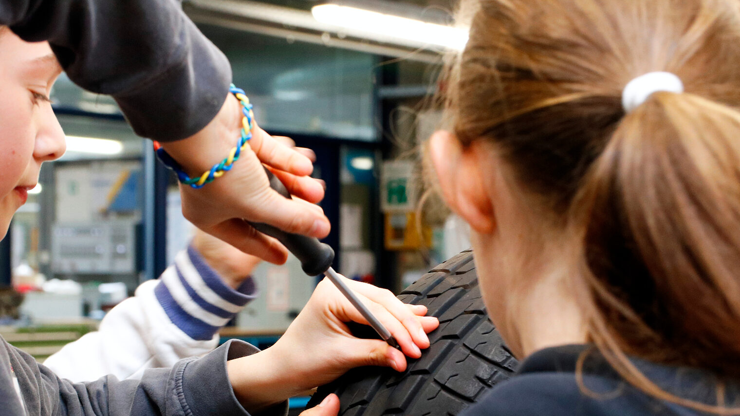 Zu sehen sind Mädchen beim Girls’Day in der Bildungsakademie der Handwerkskammer, an einem Reifen arbeiten.