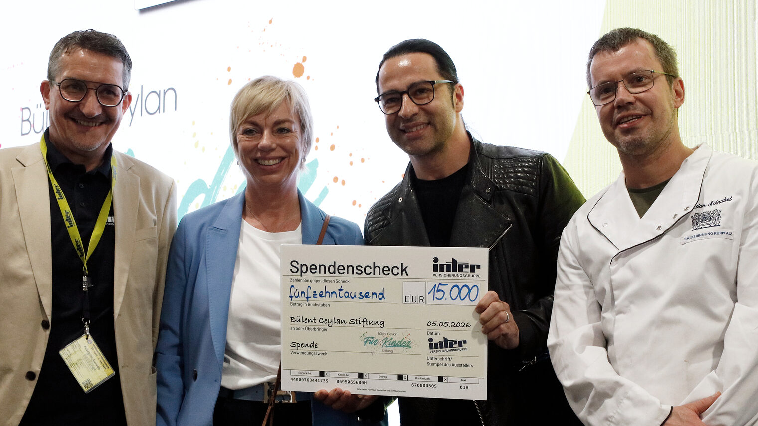 4 Personen bei der Überreichung eines Spendenschecks in Höhe von 15.000,- an die Bülent Ceylan für Kinder Stiftung