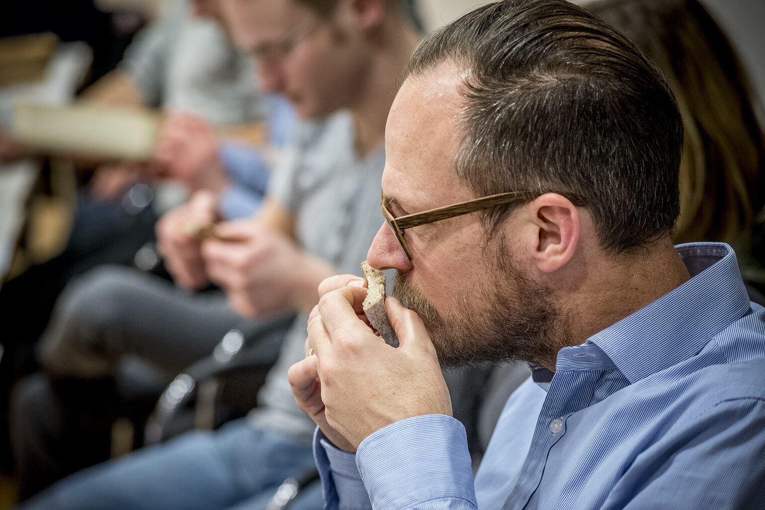 Teilnehmer der Brot-Sommelier-Weiterbildung riecht konzentriert an einem Stück Brot während einer sensorischen Prüfung
