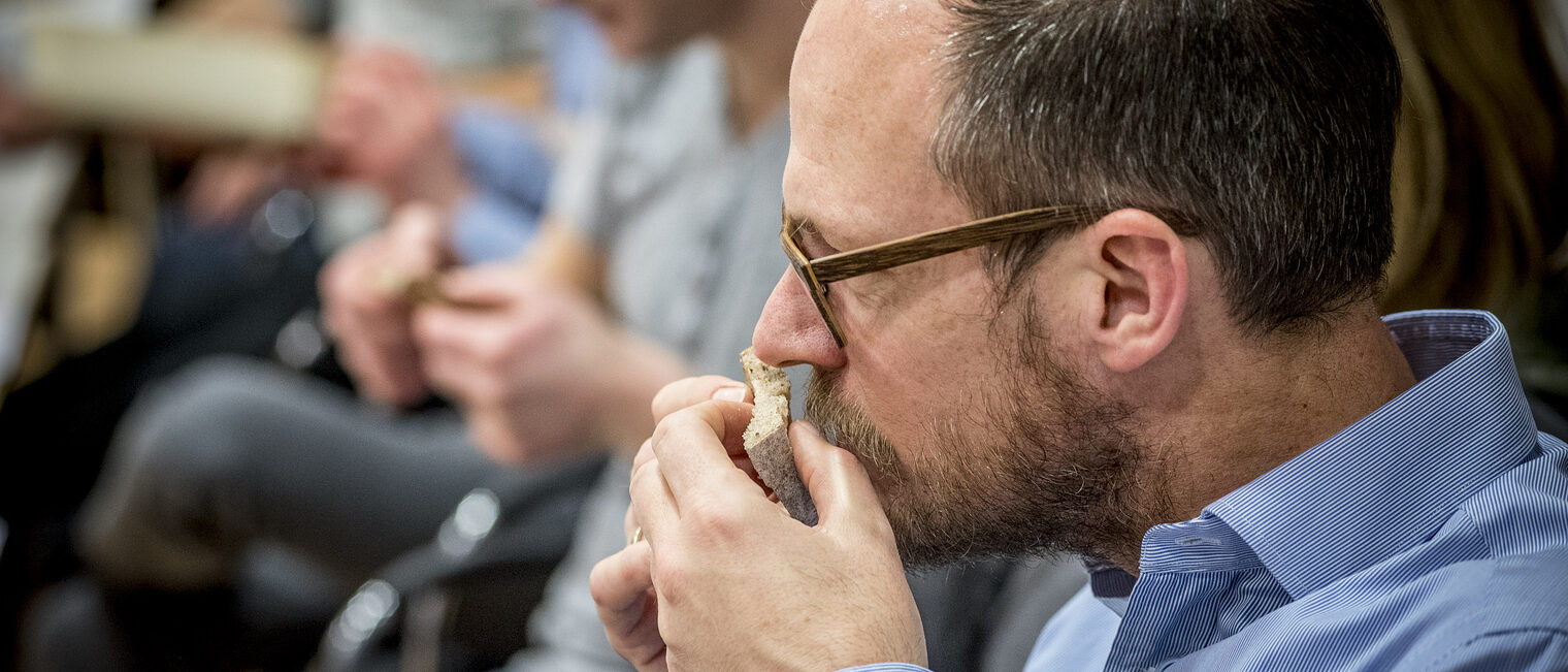 Teilnehmer der Brot-Sommelier-Weiterbildung riecht konzentriert an einem Stück Brot während einer sensorischen Prüfung